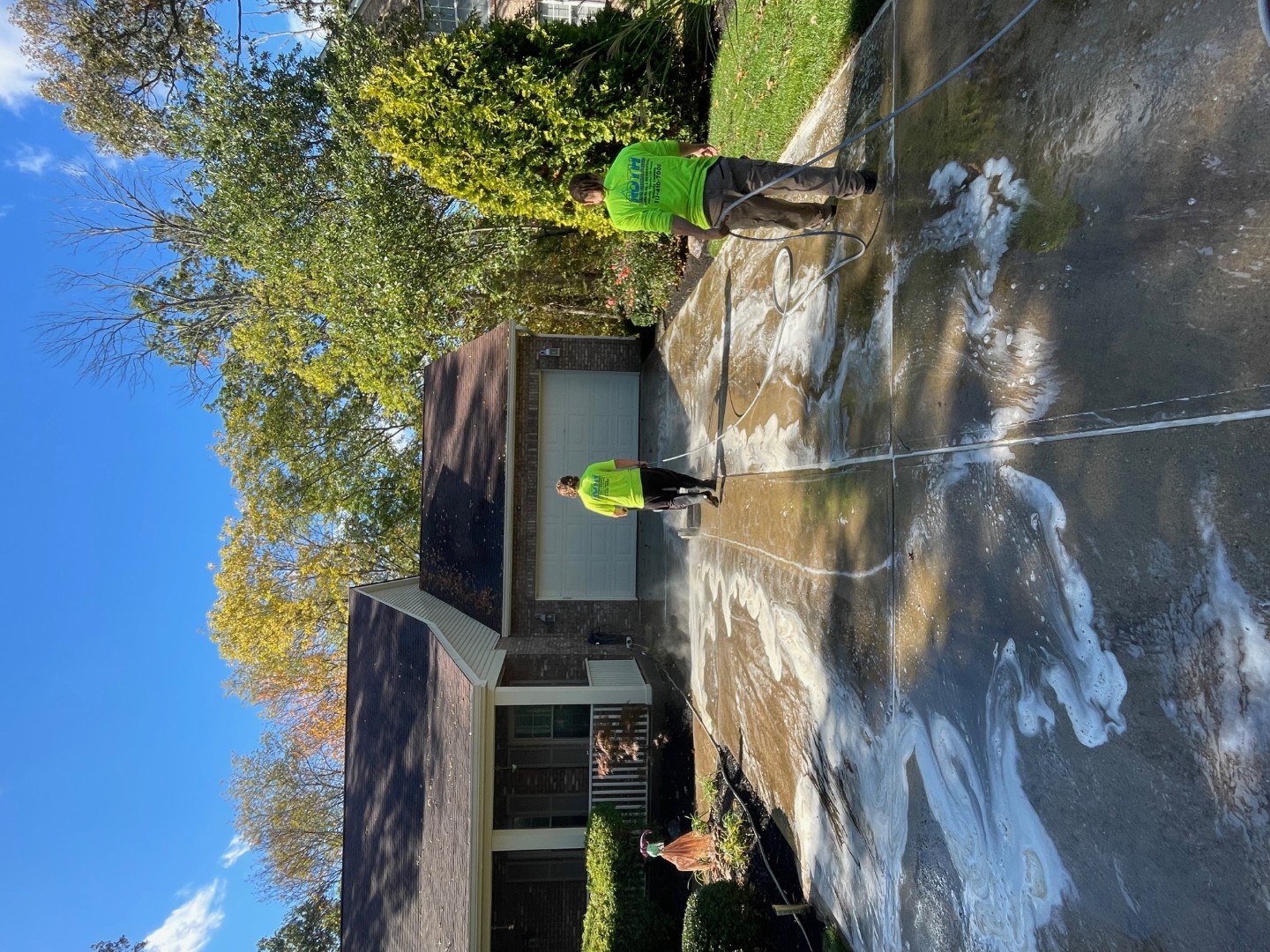 cleaning crew pressure washing a concrete driveway